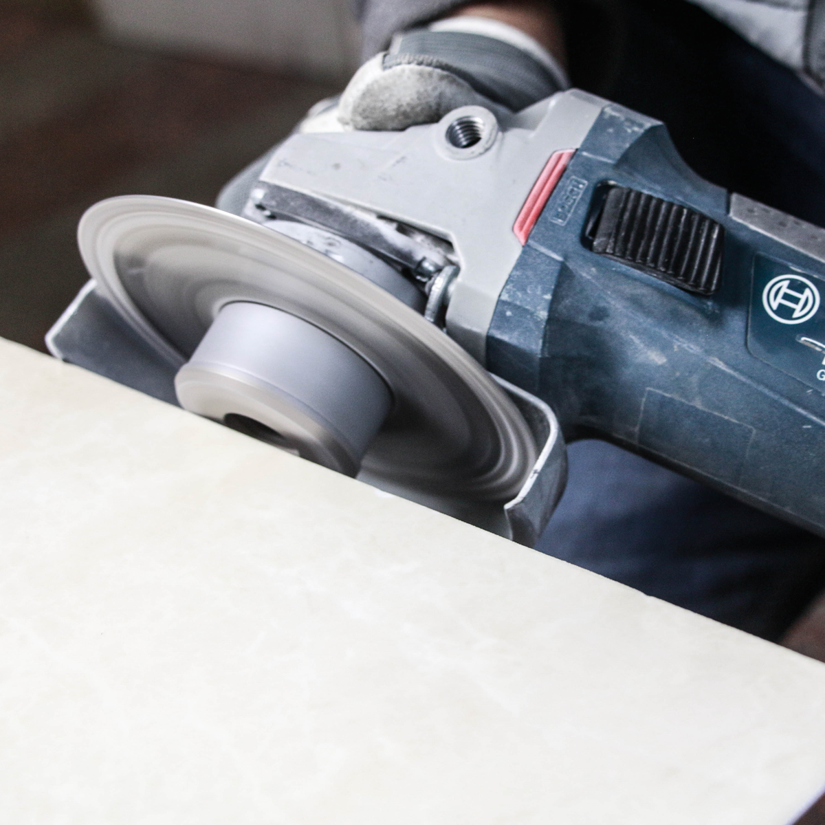 Person using a Bosch angle grinder on a concrete surface