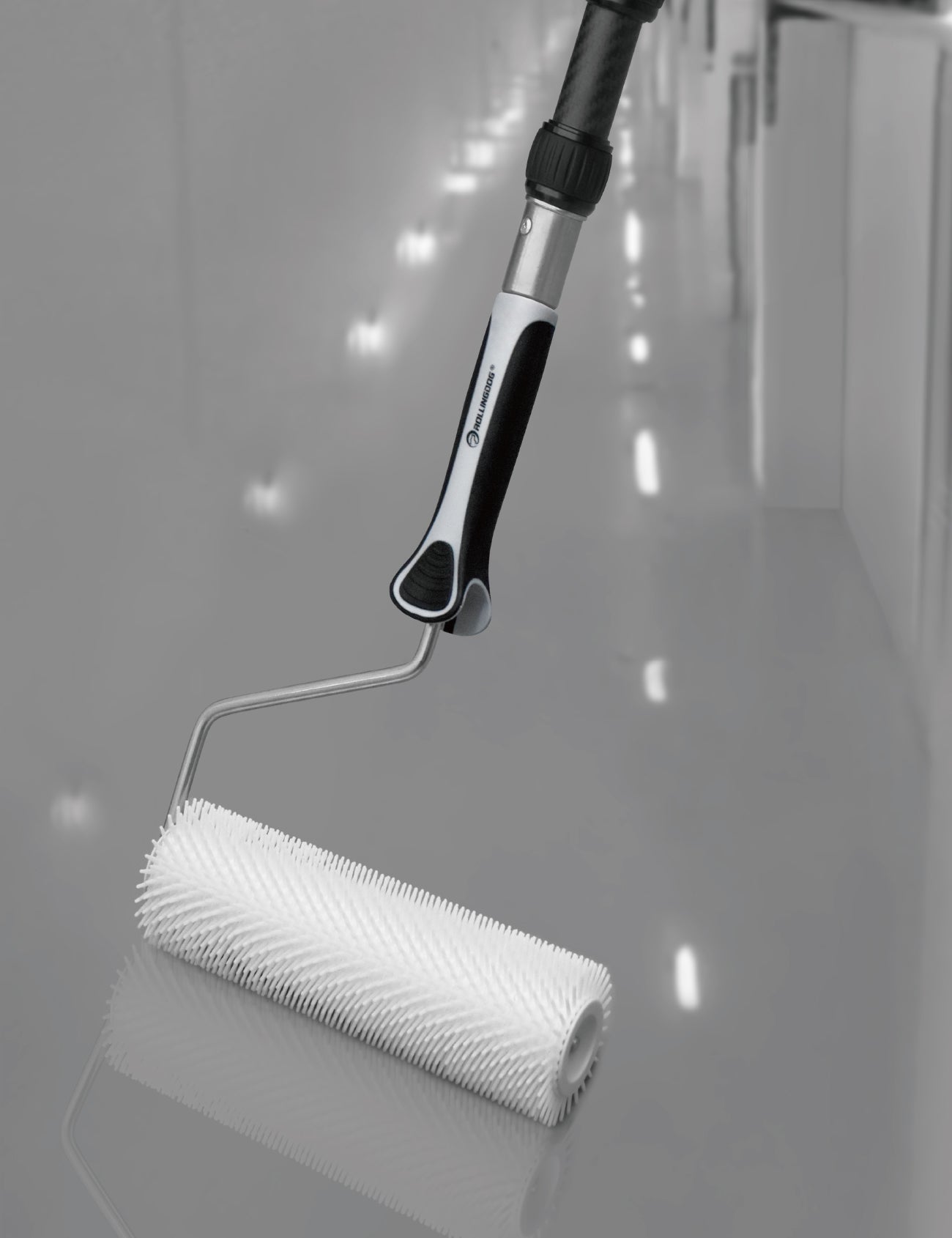 Contractor using spiked roller on epoxy-coated floor with extension pole
