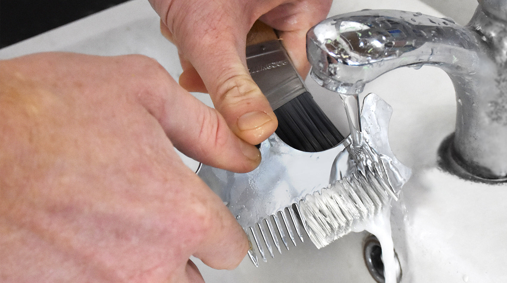Person cleaning a paint brush with a multifunction tool