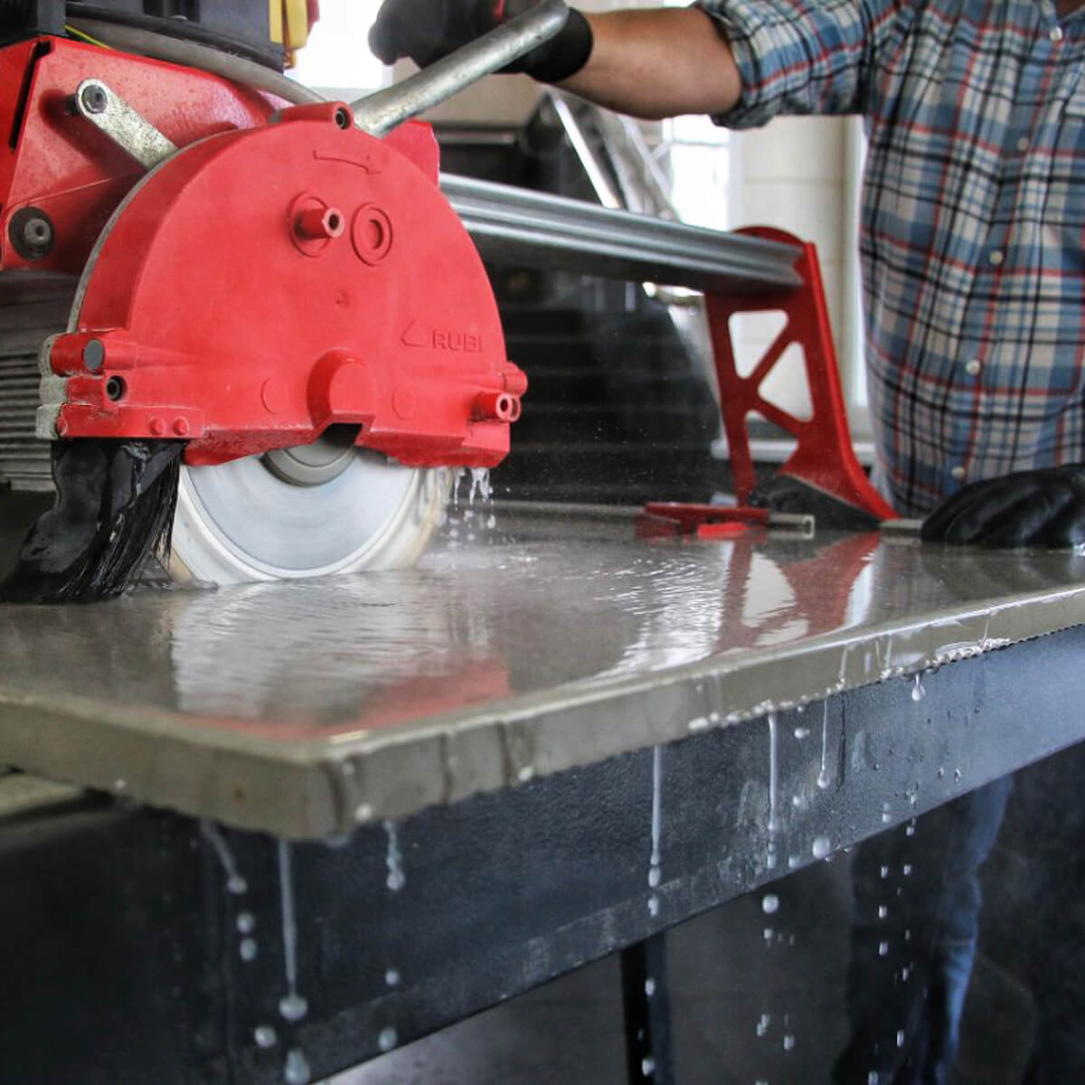 Red circular saw in use on a metal surface with a person partially visible.