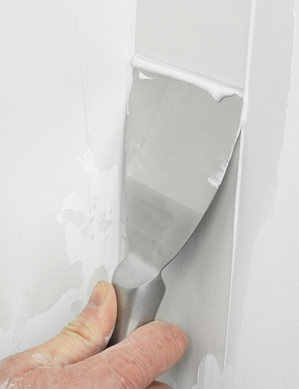 50473-Painter using 4 inch Flexible Joint Knife for patching nail holes