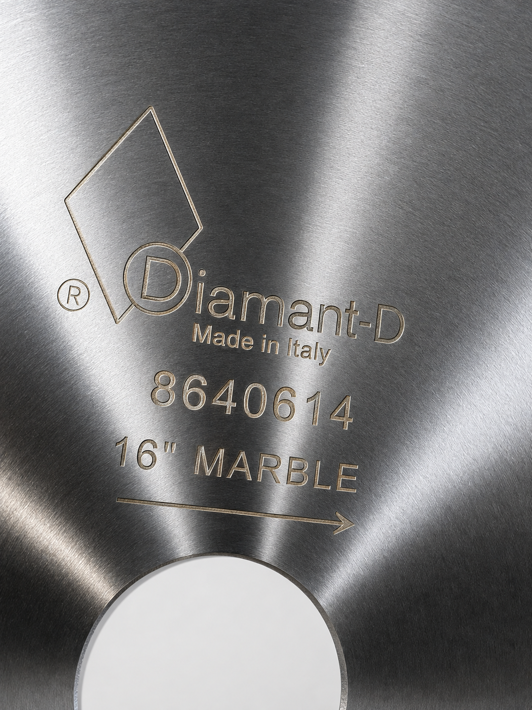 Close-up of a brushed metallic circular product surface with engraved text reading 'Diamant-D', 'Made in Italy', '8640614', and '16" MARBLE', plus a white oval section at the bottom.
