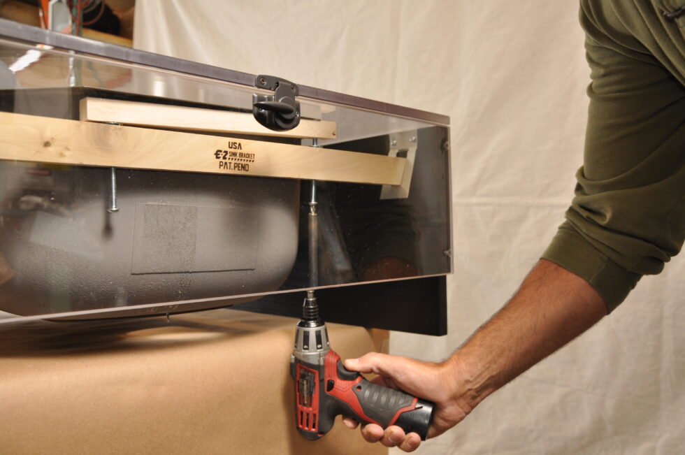 Installer fastening E-Z Sink Bracket beneath sink